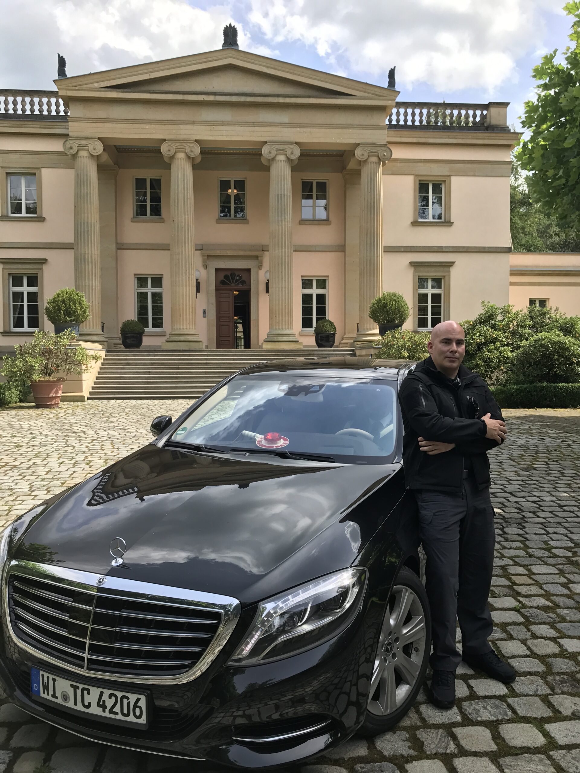 Personenschützer neben dem Fahrzeug vor einer Residenz